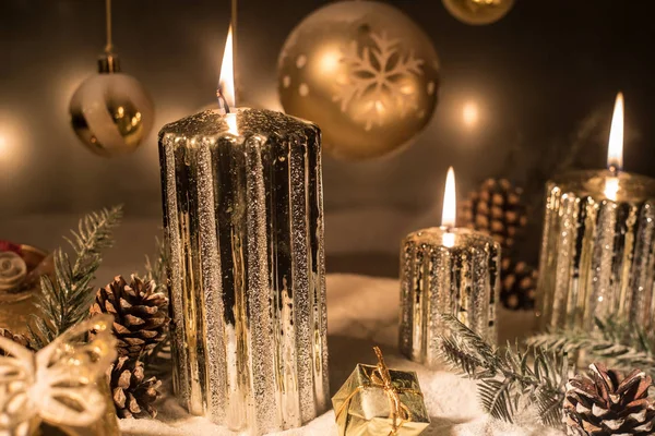 Decorazione artistica creativa. Decorazione natalizia con candele accese su sfondo scuro. Ornamenti natalizi su sfondo dorato scuro con luci . — Foto Stock