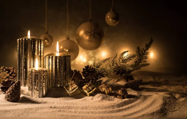 Decorazione artistica creativa. Decorazione natalizia con candele accese su sfondo scuro. Ornamenti natalizi su sfondo dorato scuro con luci . — Foto Stock