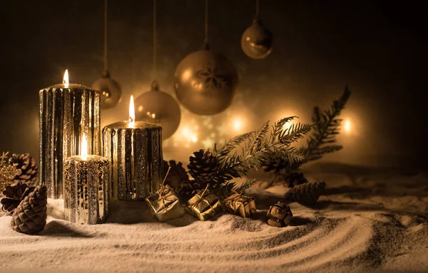 Decoración artística creativa. Decoración navideña con velas encendidas sobre un fondo oscuro. Adornos navideños sobre fondo dorado oscuro con luces . —  Fotos de Stock