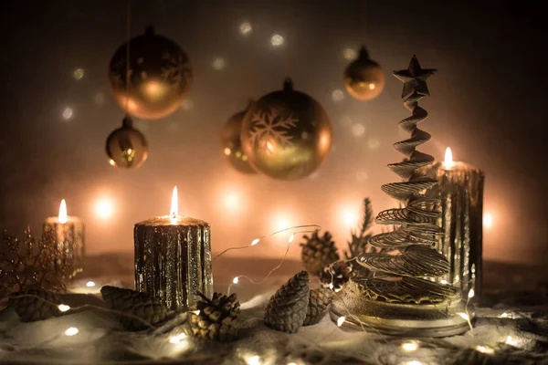 Decorazione artistica creativa. Decorazione natalizia con candele accese su sfondo scuro. Ornamenti natalizi su sfondo dorato scuro con luci . — Foto Stock