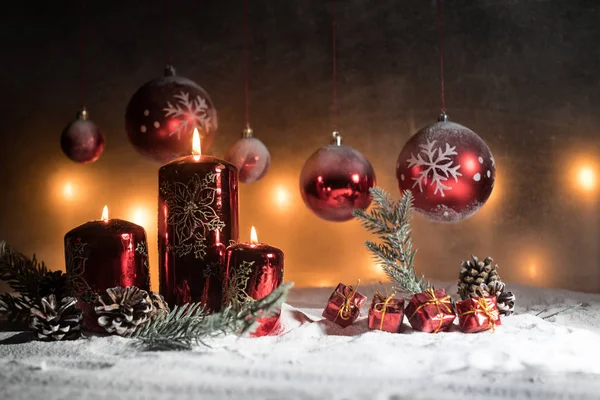 Decorazione artistica creativa. Decorazione natalizia con candele accese su sfondo scuro. Ornamenti natalizi su sfondo dorato scuro con luci . — Foto Stock