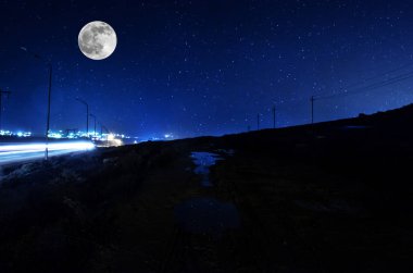 Uzun pozlu çekim. Dolunay gecesi ormanın içinden geçen Dağ Yolu. Koyu mavi gökyüzü ve ay manzarası. Azerbaycan
