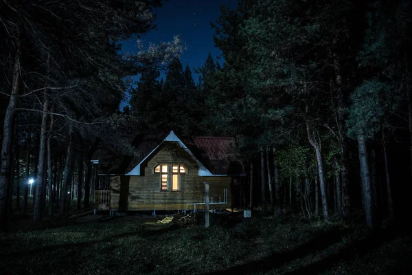 Старый жуткий домик в сосновом лесу ночью. Концепция Хэллоуина ужасов — стоковое фото
