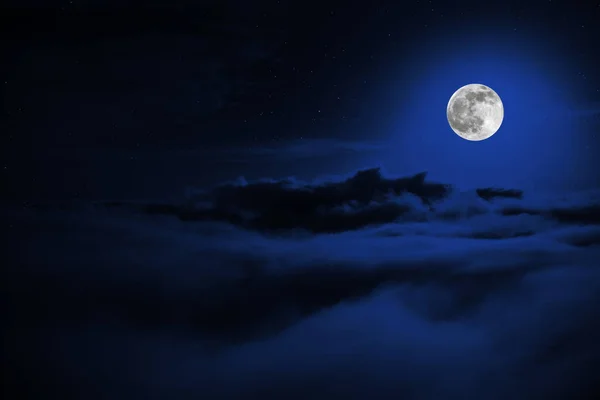 Skinet cirkel av månen i mörkret på en bakgrund av stjärna himmel och moln — Stockfoto