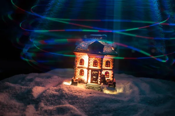 Nieuwjaar miniatuur huis in de sneeuw 's nachts met dennenboom. Vakantie concept. Selectieve focus — Stockfoto