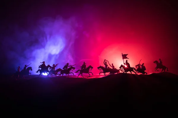 Adegan pertempuran abad pertengahan dengan kavaleri dan infanteri. Siluet figur sebagai objek terpisah, bertarung antara prajurit dengan latar belakang berkabut gelap. Adegan malam . — Stok Foto
