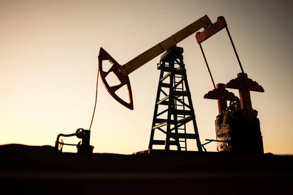 Decoração de arte criativa. Bomba de óleo e fábrica de refino de óleo ao pôr do sol. Conceito industrial de energia. Foco seletivo . — Fotografia de Stock