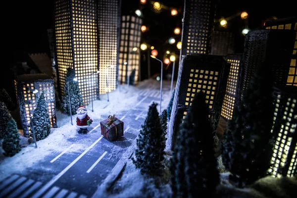 Little miniature city with road and lights. Decorative cute small houses in snow at night in winter. Creative Holiday concept. Christmas and New Year attributes decorated composition. — Stock Photo, Image