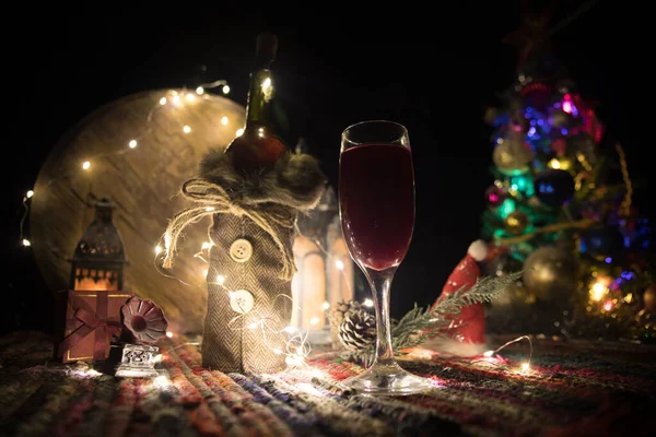 Red wine in crystal glass with bottle on colorful carpet with creative New Year artwork decorations. Copy space — Stockfoto