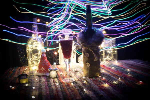 Vinho tinto em vidro de cristal com garrafa em tapete colorido com decorações criativas de arte de Ano Novo. Espaço de cópia — Fotografia de Stock