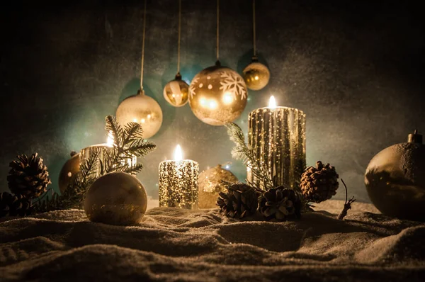 Decorazione artistica creativa. Decorazione natalizia con candele accese su sfondo scuro. Ornamenti natalizi su sfondo dorato scuro con luci . — Foto Stock