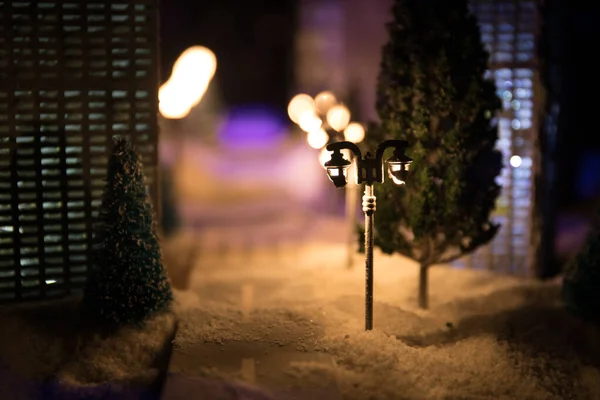 Kleine miniatuurstad met weg en licht. Decoratieve schattige huisjes in de sneeuw 's nachts in de winter. Creatieve vakantie concept. Kerst en Nieuwjaar attributen versierd samenstelling. — Stockfoto