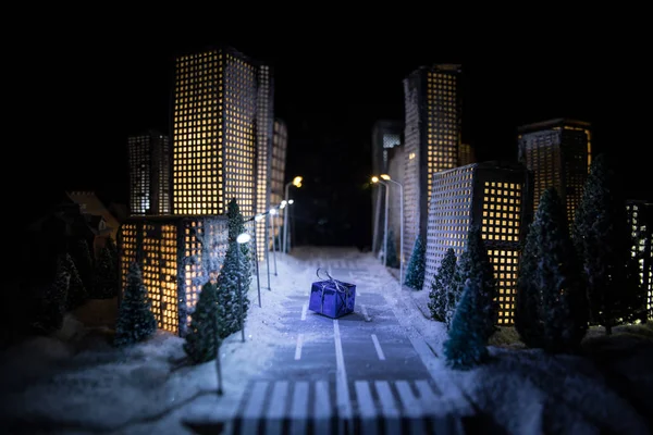 Kleine miniatuurstad met weg en licht. Decoratieve schattige huisjes in de sneeuw 's nachts in de winter. Creatieve vakantie concept. Kerst en Nieuwjaar attributen versierd samenstelling. — Stockfoto