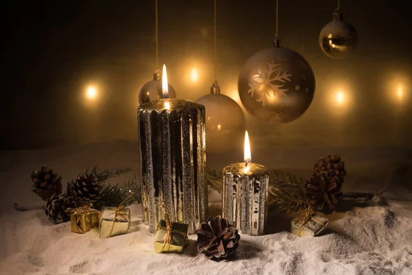 Decorazione artistica creativa. Decorazione natalizia con candele accese su sfondo scuro. Ornamenti natalizi su sfondo dorato scuro con luci . — Foto Stock