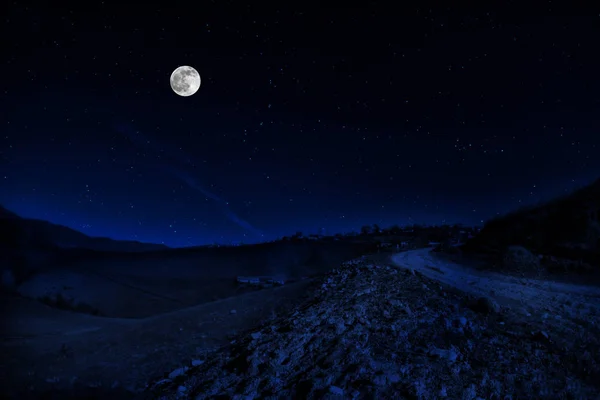 Hosszú lövés. Hegyi út az erdőn keresztül teliholdkor. Színes éjszakai táj sötétkék égbolttal és holddal. Azerbajdzsán — Stock Fotó