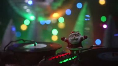 Noel Baba figürü ve renkli ışıklar altında DJ karıştırma tahtasıyla Noel kompozisyonu yakın çekim görüntüleri