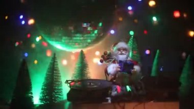 Noel Baba figürü ve renkli ışıklar altında DJ karıştırma tahtasıyla Noel kompozisyonu yakın çekim görüntüleri