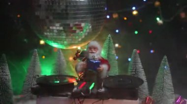 Noel Baba figürü ve renkli ışıklar altında DJ karıştırma tahtasıyla Noel kompozisyonu yakın çekim görüntüleri