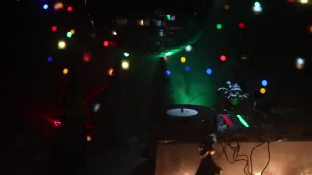 サンタクロース像とDjミキシングボードをカラフルなライトの下でクリスマスの組成物のクローズアップ映像 — ストック動画