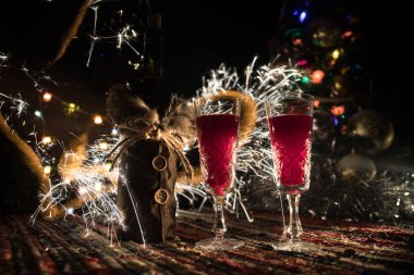 Kırmızı şarap kristal bardakta, renkli halıda şişe ve yaratıcı yeni yıl süslemeleri. Boşluğu kopyala