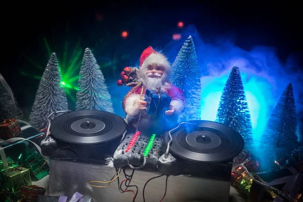 Dj mixer with headphones on dark nightclub background with Christmas tree New Year Eve. Close up view of New Year elements on a Dj table. Holiday party concept. Empty space