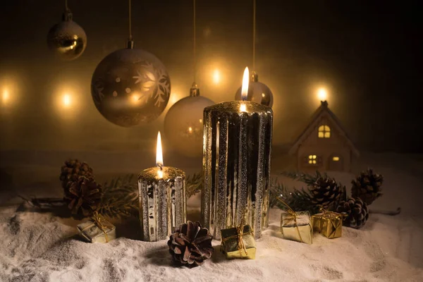 Decorazione artistica creativa. Decorazione natalizia con candele accese su sfondo scuro. Ornamenti natalizi su sfondo dorato scuro con luci . — Foto Stock