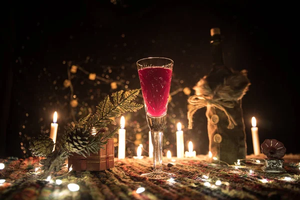 Červené víno v křišťálovém skle s lahví na barevném koberci s kreativní novoroční výzdobou. Kopírovat prostor — Stock fotografie