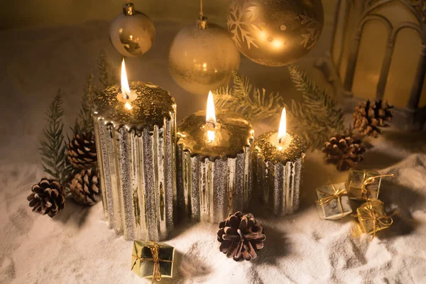 Decorazione artistica creativa. Decorazione natalizia con candele accese su sfondo scuro. Ornamenti natalizi su sfondo dorato scuro con luci . — Foto Stock