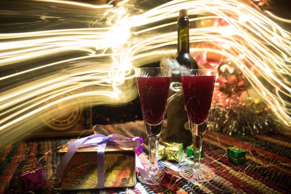 Vino tinto en cristal con botella en alfombra de colores con decoraciones creativas de Año Nuevo. Copiar espacio — Foto de Stock