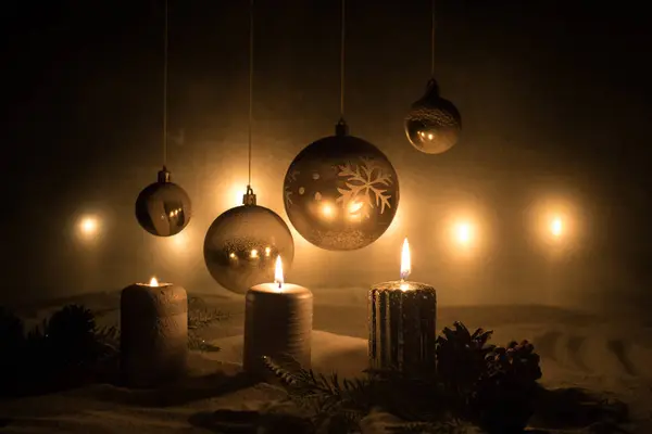 Décoration artistique créative. Décoration de Noël avec des bougies allumées sur un fond sombre. Ornements de Noël sur fond doré foncé avec des lumières . — Photo