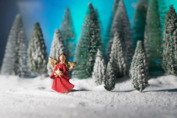 Little white guardian angel in snow. Festive background. Christmas decorations.