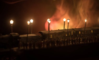 Sisli arka planda eski bir trenin önünde duran kalabalığın siluetleri. Seçici odaklanma. Oyuncak trenle yaratıcı sanat dekorasyonu