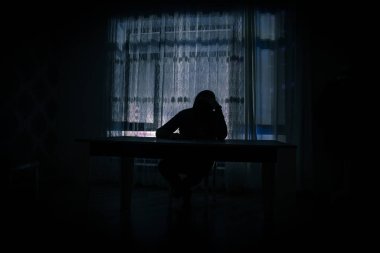 Odanın penceresinde duran bir adamın silüeti. Karanlık odanın penceresinde eski model bir fenerle çekilmiş fantezi bir resim..