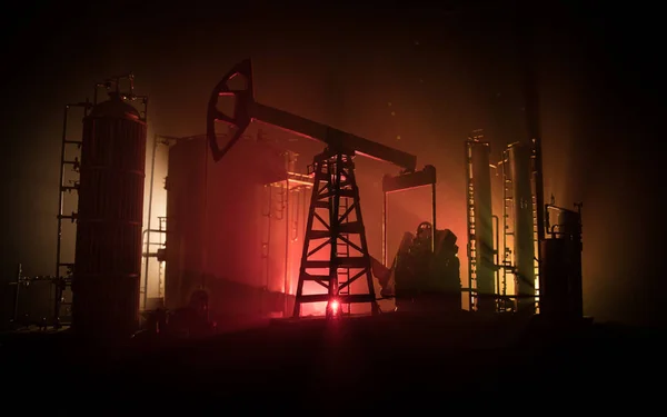 Decoración de obra. Bomba de aceite y plataforma de aceite máquinas industriales de energía para el petróleo por la noche con niebla y contraluz. Fábrica de refino de petróleo. Concepto industrial energético. Enfoque selectivo — Foto de Stock