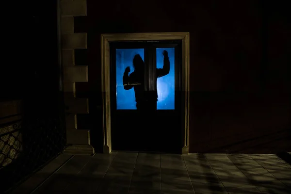 La silhouette d'un humain devant une fenêtre la nuit. Scène effrayante concept halloween de silhouette floue de maniaque . — Photo
