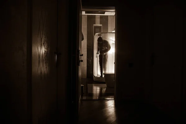 Horror-Silhouette einer Person im Fenster. Gruseliges Halloween-Konzept verschwommene Silhouette einer Hexe im Badezimmer. Dekoriert mit Feuerwerk — Stockfoto