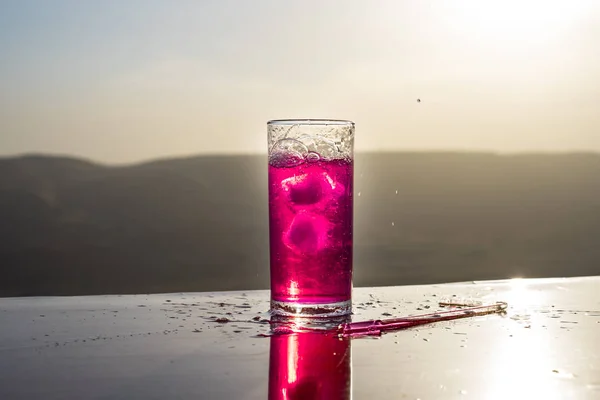 Koncepcja letniego napoju chłodzącego. Kieliszki koktajlowe rozpryskiwania na zachód słońca. Z bliska mokra szklanka zimnego napoju na tarasie. — Zdjęcie stockowe