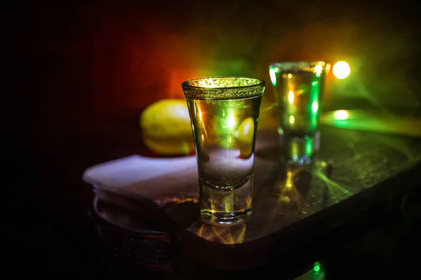 Concept de boisson club. Savoureux cocktail de boissons alcoolisées tequila au citron vert et au sel sur fond sombre vibrant ou verres à la tequila dans un bar — Photo