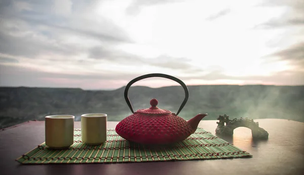 Tea concept. Japanese tea ceremony culture east beverage. Teapot and cups on table with bamboo leaves on sunset — Stock Photo, Image