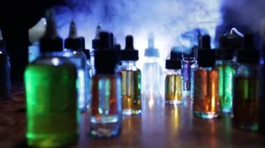Vape konsepti. Karanlık arka planda duman bulutları ve tüp sıvısı şişeleri. Işık efektleri. Arka plan, vape reklamı ya da vape arkaplan olarak kullanışlı. Seçici odak