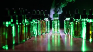 Vape konsepti. Karanlık arka planda duman bulutları ve tüp sıvısı şişeleri. Işık efektleri. Arka plan, vape reklamı ya da vape arkaplan olarak kullanışlı. Seçici odak