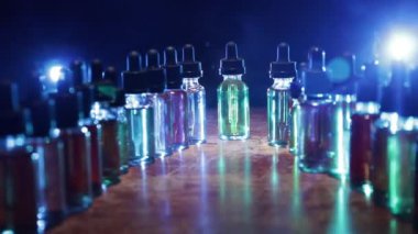 Vape konsepti. Karanlık arka planda duman bulutları ve tüp sıvısı şişeleri. Işık efektleri. Arka plan, vape reklamı ya da vape arkaplan olarak kullanışlı. Seçici odak