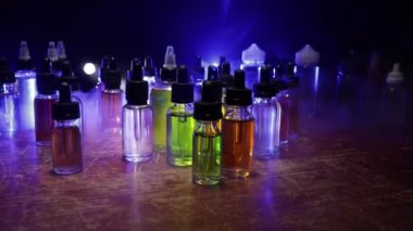 Vape konsepti. Karanlık arka planda duman bulutları ve tüp sıvısı şişeleri. Işık efektleri. Arka plan, vape reklamı ya da vape arkaplan olarak kullanışlı. Seçici odak