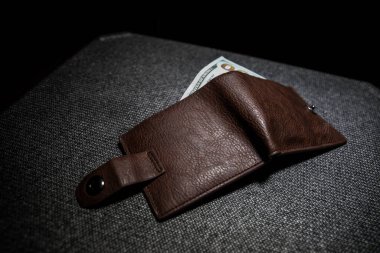 Ahşap arka planda parası olan şık bir erkek çantası. Para, kredi ve banka kartlarıyla dolu bir erkek cüzdanı.