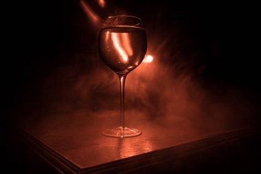 Ahşap masada şarap kadehi ve arka planda güzel renkli ışıklar. Karanlık arka planda şarap kadehleri. Seçici odaklanma. Kulüp içki konsepti