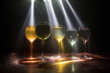 Ahşap masada şarap kadehi ve arka planda güzel renkli ışıklar. Karanlık arka planda şarap kadehleri. Seçici odaklanma. Kulüp içki konsepti