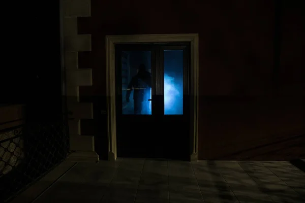 閉じたガラスのドアを通ってドアの上に未知の影の姿のシルエット 夜の窓の前に人間のシルエット 怖いシーンハロウィンの概念のぼやけたシルエットのマニアック — ストック写真