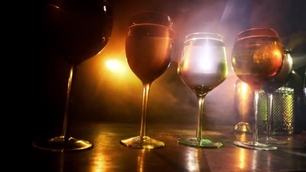 背景に美しいトーンのライトと木製のテーブルの上のワインのゴブレット 暗い背景にワインのグラス 選択的フォーカス クラブドリンクのコンセプト — ストック動画