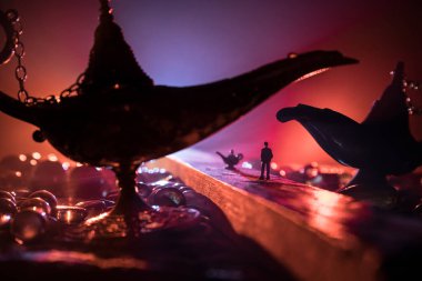 Lamp of wishes concept. Silhouette of a man standing in the middle of the road on a misty night with giant Antique Aladdin arabian nights genie style oil lamp. Creative artwork decoration
