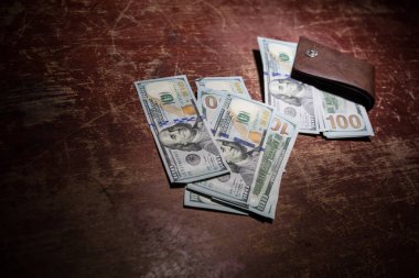 Ahşap arka planda parası olan şık bir erkek çantası. Para, kredi ve banka kartlarıyla dolu bir erkek cüzdanı.